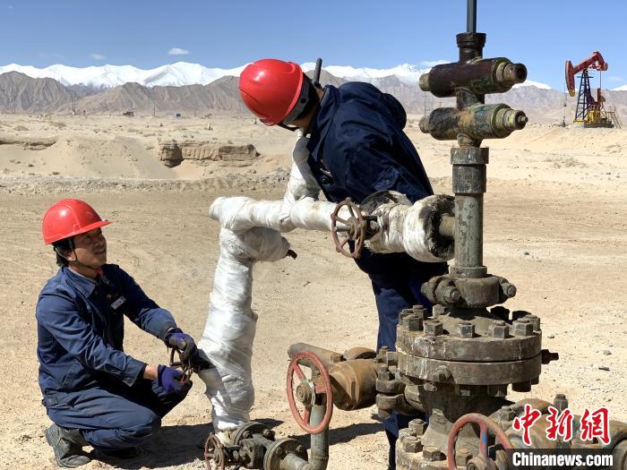 图为刘富强(左)与工友一同检测油井设备参数。 孙睿 摄