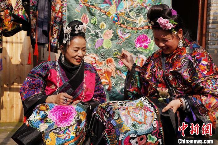 图为张艳梅(左)与绣娘一起绣苗绣。 受访者供图